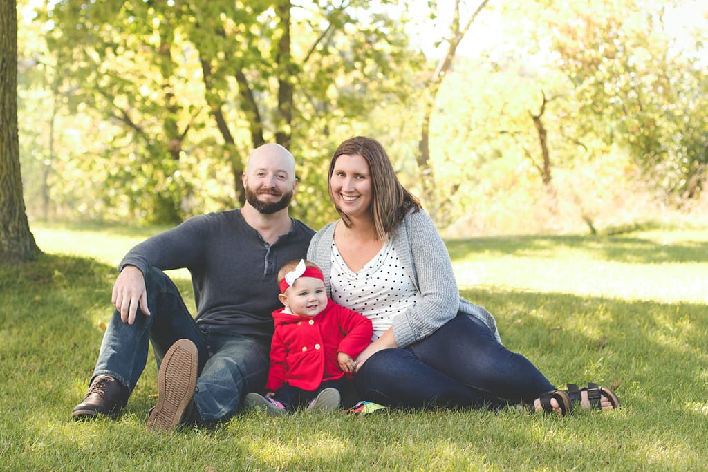 family posing by tree with red jacket